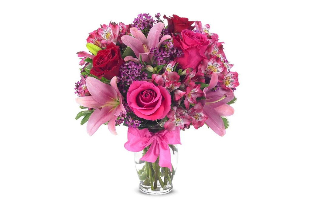 Pink and red roses and lilies in a clear vase