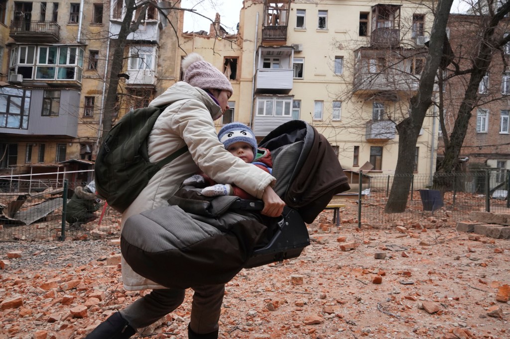 A woman in Ukraine evacuates with a child.