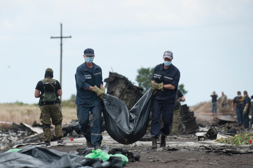 Ukrainian emergency workers carry a victim's body in a bag, at the crash site of Malaysia Airlines Flight 17 near the village of Hrabove, Russian-controlled Donetsk region of eastern Ukraine, Sunday, July 20, 2014. 