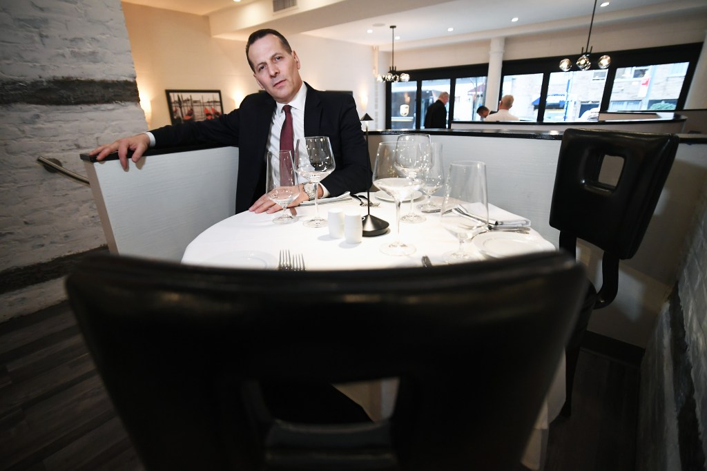 Steve Haxhiaj is pictured sitting at a booth in the restaurant. 