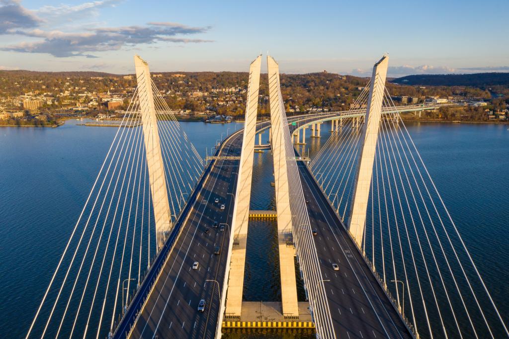 An aerial shot of the Mario M Cuomo Bridge on a bright day with land in the distance