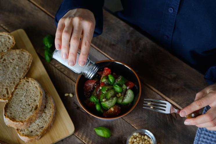 Person pouring salt on food