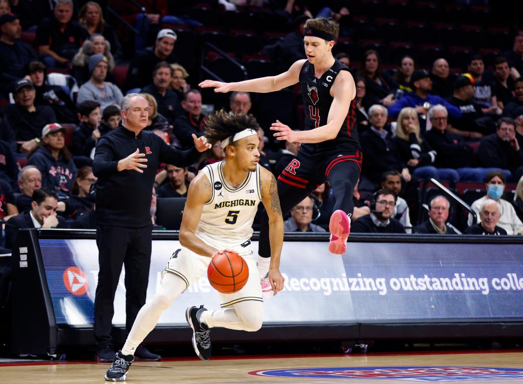 Rutgers guard Paul Mulcahy (4) tries to guard Michigan forward Terrance Williams II (5) as Rutgers coach Steve Pikiell gestures from the sideline.