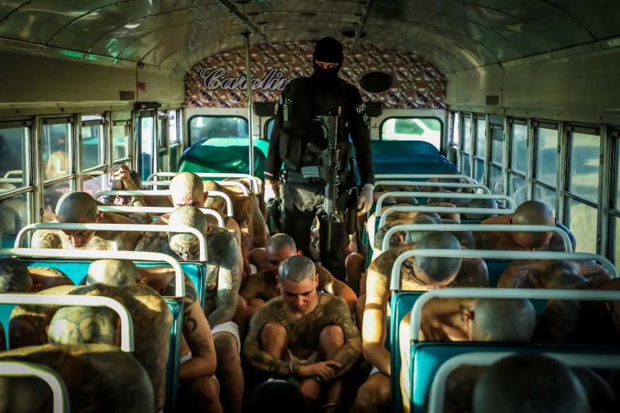 A prison agent guards gang members as they are transported to their cells.