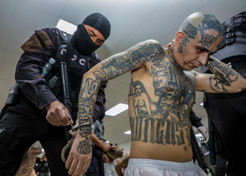 A prison agent guards a gang member.