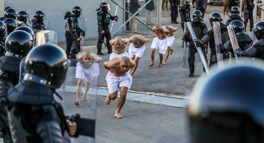 Prison agents observe gang members as they are processed.