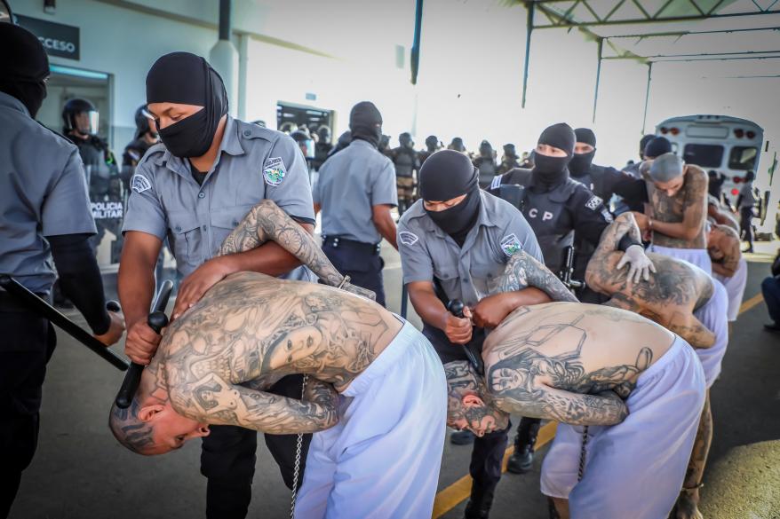 Prison agents guard gang members as they are processed.