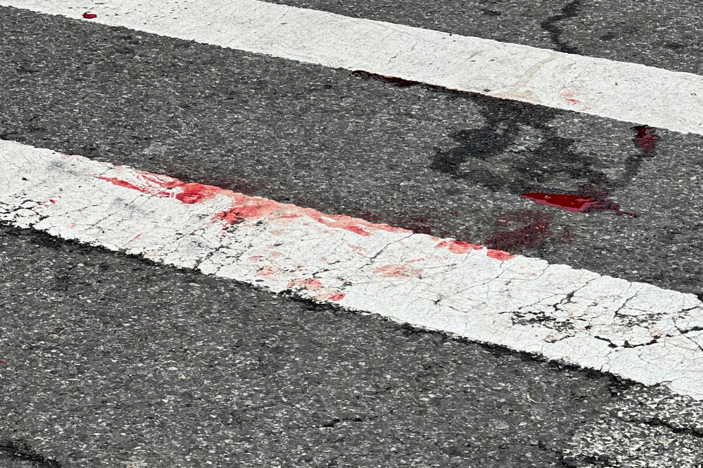 A white crosswalk line with red blood stains.