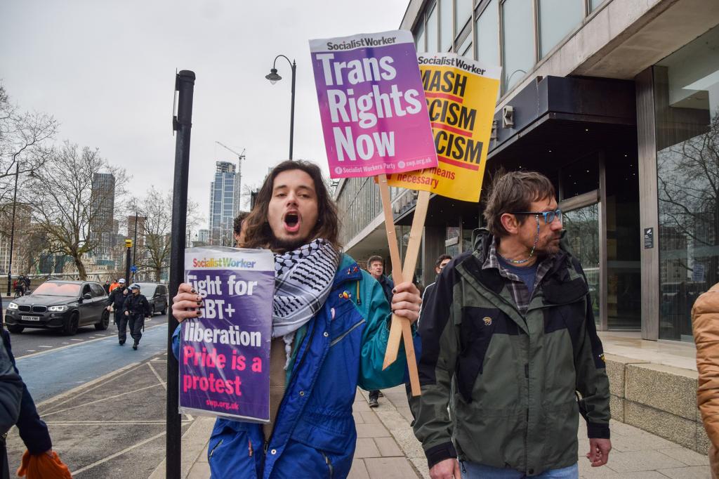 Pro-LGBTQ rights protester holds trans rights and LGBTQ rights placards during the demonstration.