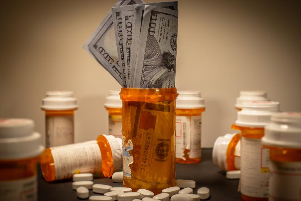 American $100 bills are stuffed into a prescription drug container.