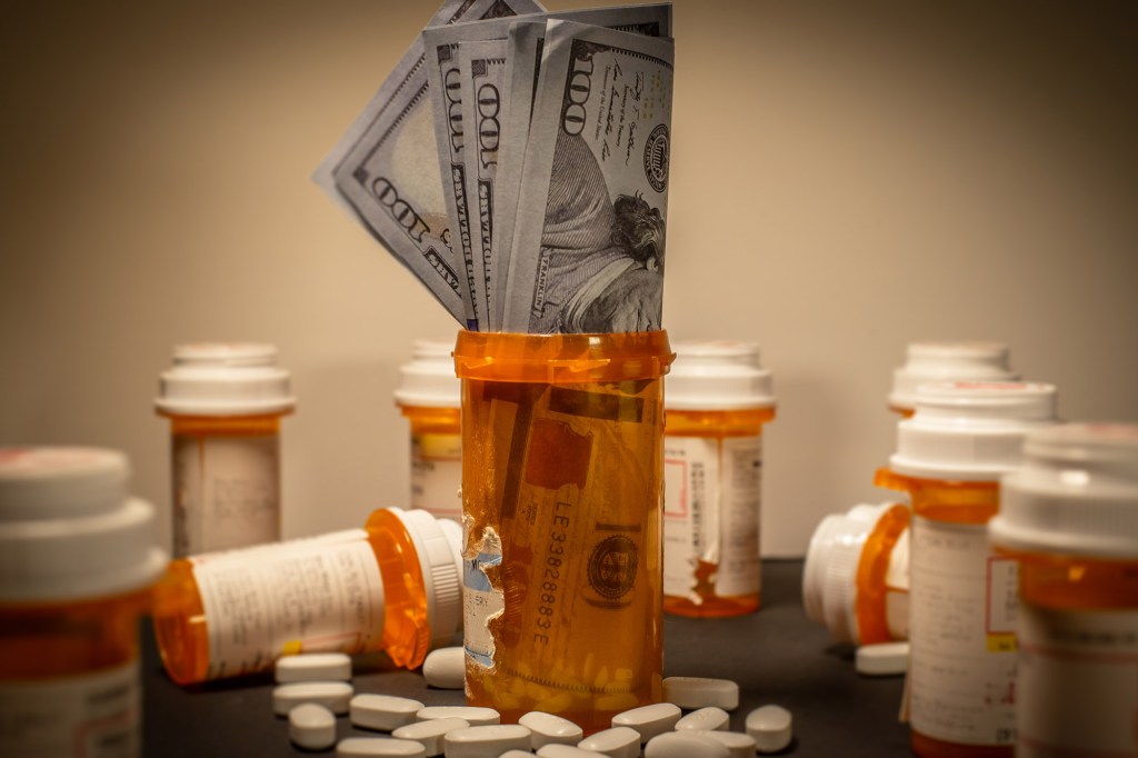 American $100 bills are stuffed into a prescription drug container.