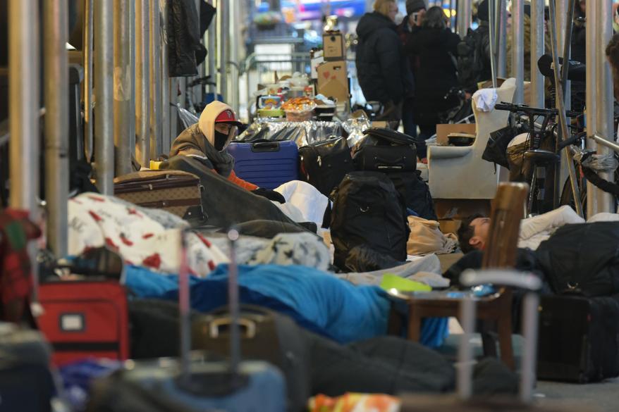 Migrants sleep on the sidewalk in front of the Watson Hotel.