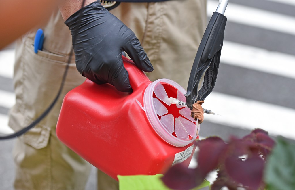 Worker puts needles in a collection container