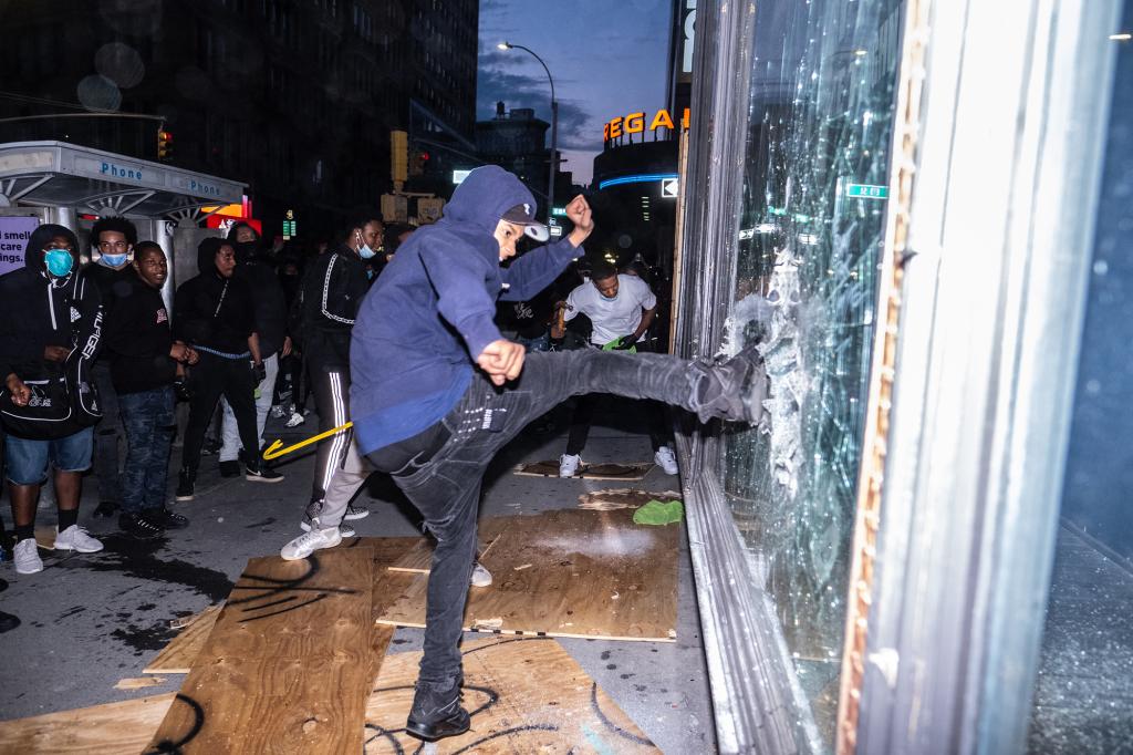 A protester smashes a storefront window.