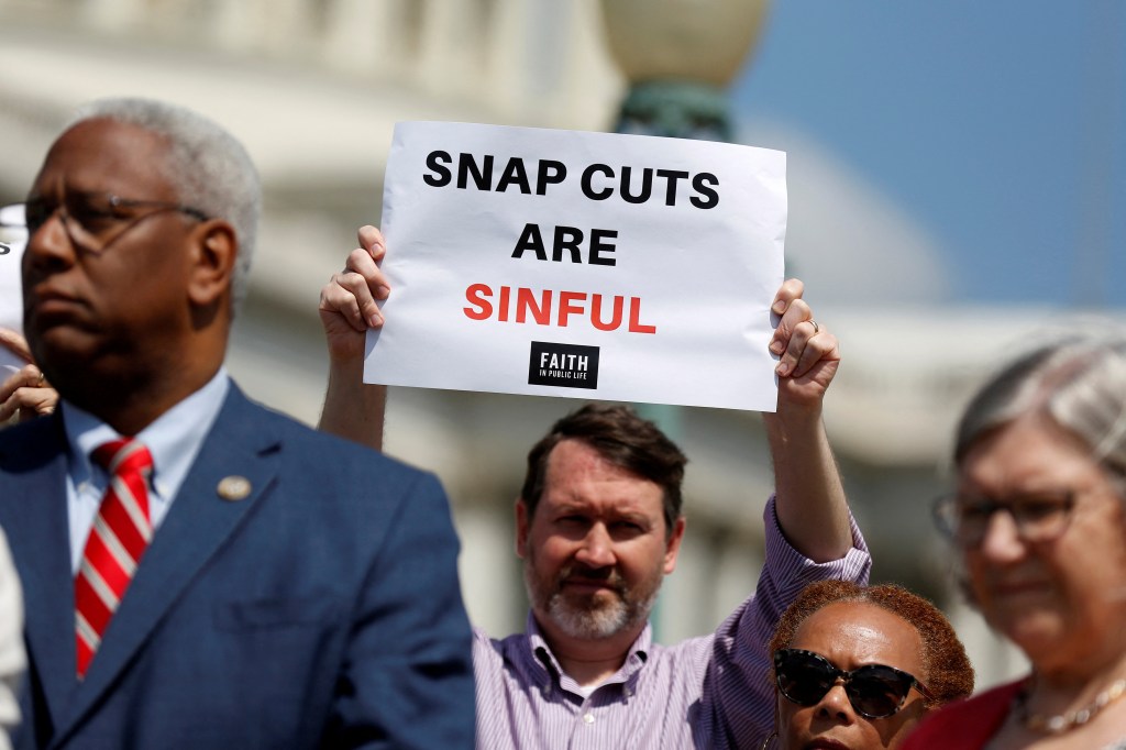 Person holding a "SNAP cuts are sinful."