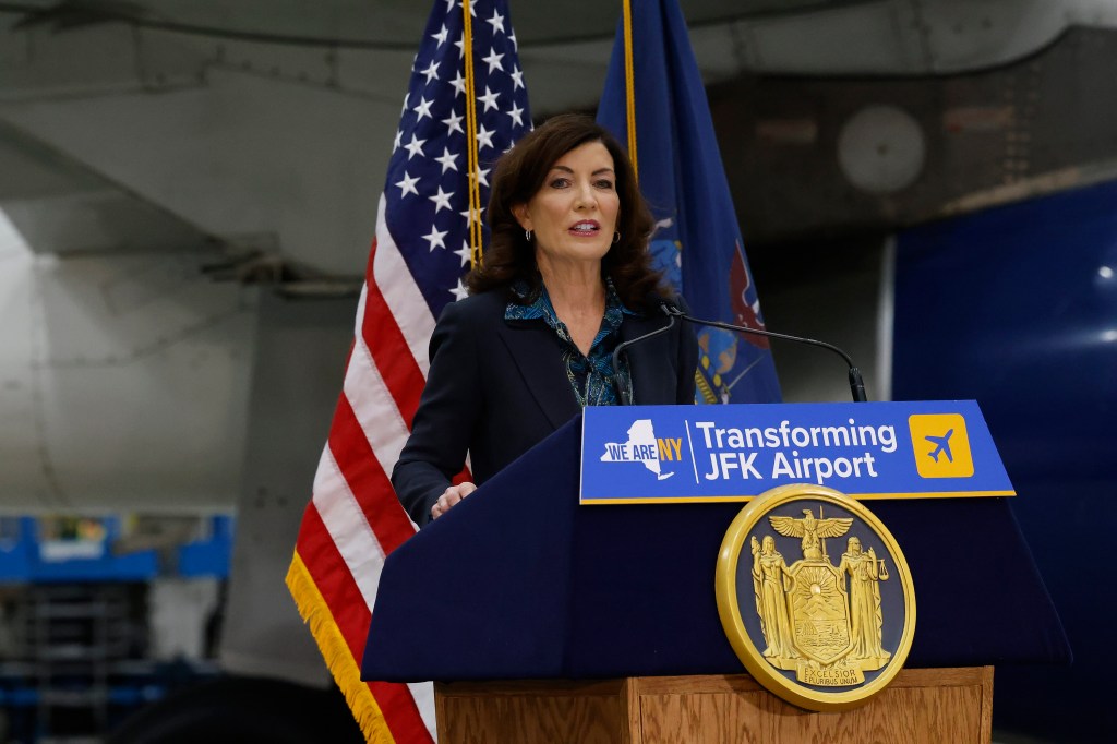 Hochul speaking at a podium in front of an American flag