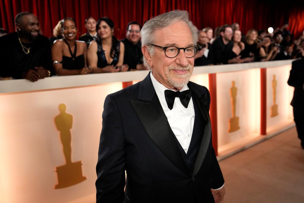 Spielberg in a tux standing in front of people at the Oscars