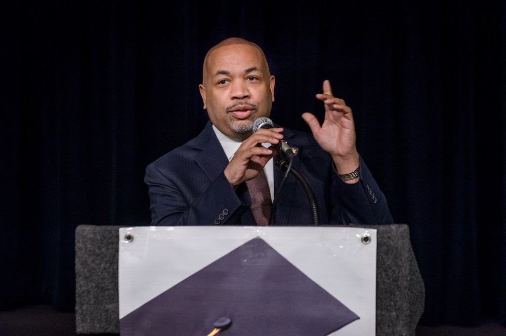 Assembly Speaker Carl Heastie speaking at a podium with a black background