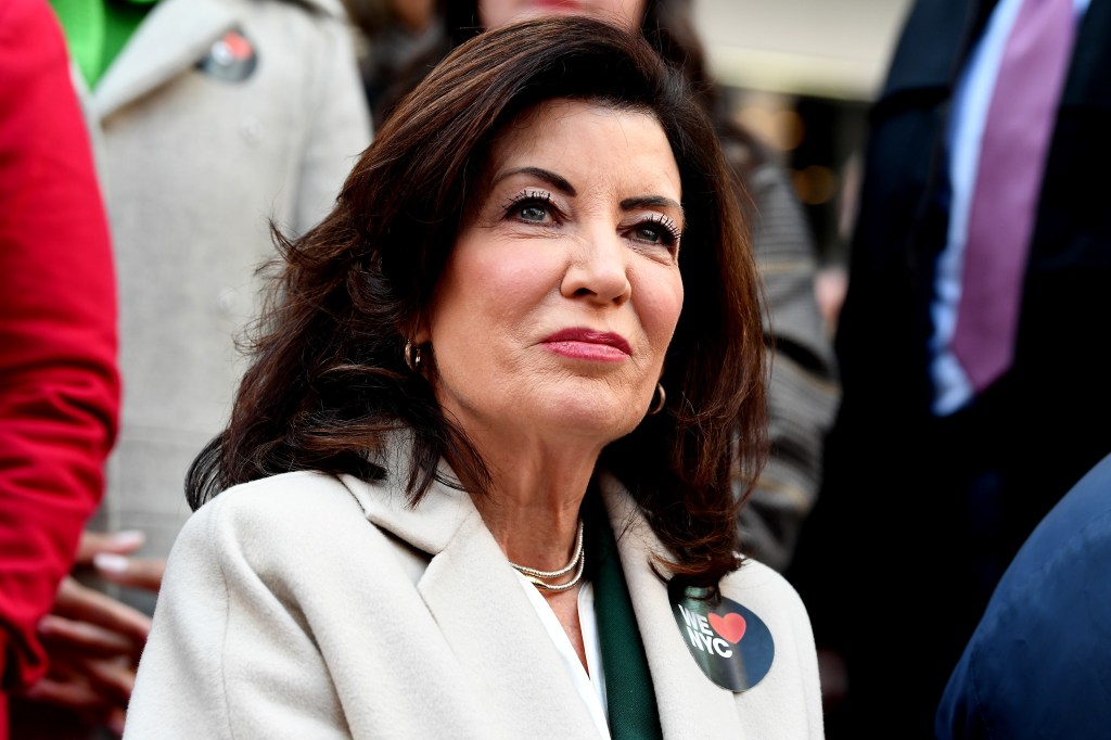 Kathy Hochul gazing past the camera in a white jacket while sitting outside