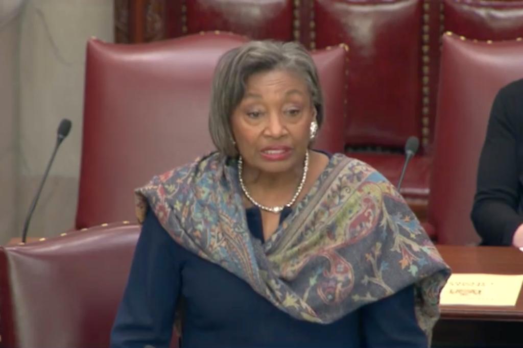 Andrea Stewart-Cousins speaking in the senate chambers with a trademark scarf.