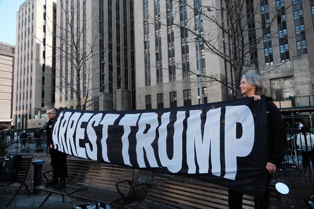 Demonstrators hold a banner that says "Arrest Trump" outside Bragg's office