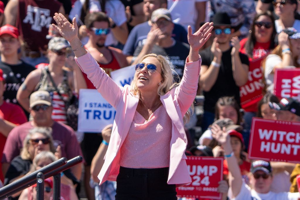 Greene holds her hands aloft in front of admirers at a Trump rally.