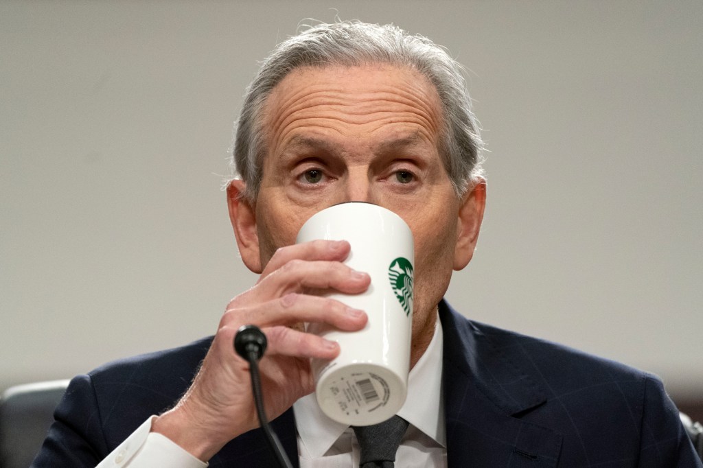 Schultz drinks from a Starbucks mug as he testifies.