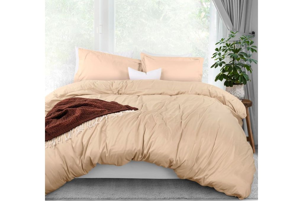 A bed with a cream colored duvet cover. 