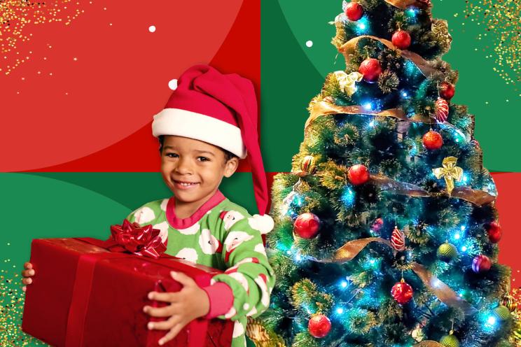 Child holding present in front of Christmas tree