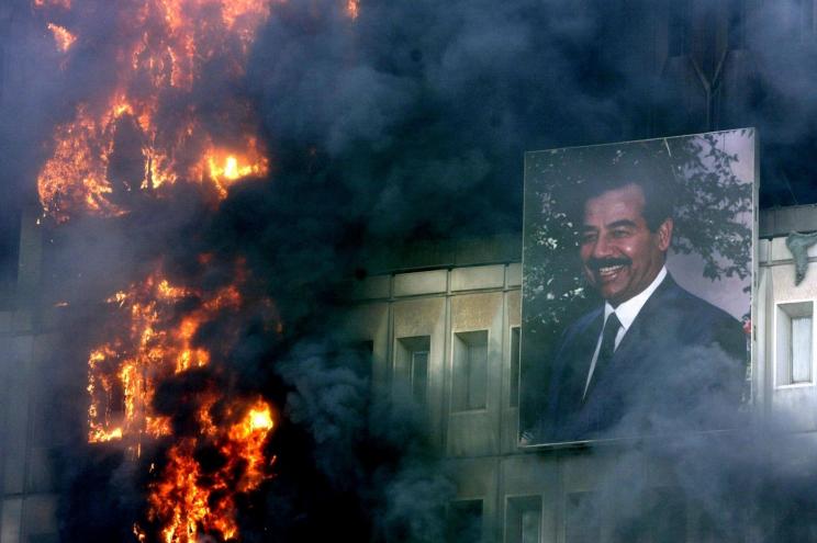 A portrait of Saddam Hussein still hangs on the burning Ministry of Transport and Communication building in Baghdad, April 9, 2003.