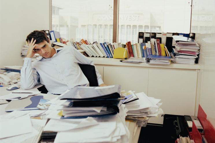 Man behind cluttered desk.