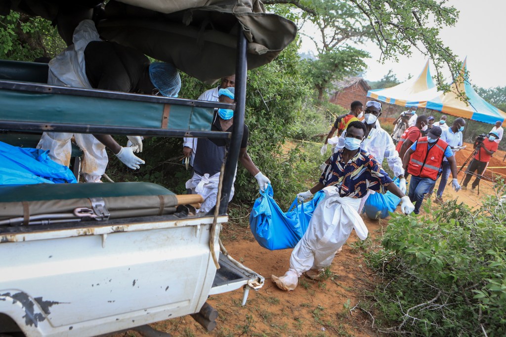 Police and local residents load the exhumed bodies of victims of a religious cult into the back of a truck in the village of Shakahola, near the coastal city of Malindi, in Kenya on April 23, 2023.