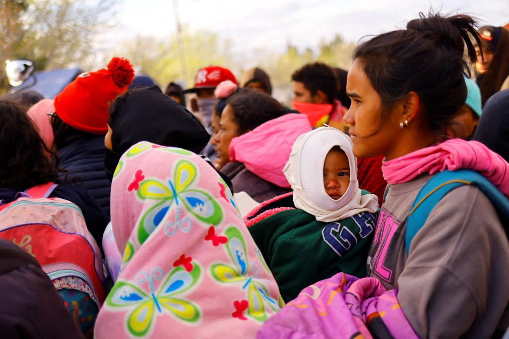 A kid is carried in arms while migrants, mostly from Venezuela and traveling by train, queue to board a bus as they try to reach the United States, in Samalayuca, on the outskirts of Ciudad Juarez, Mexico, March 17, 2023.