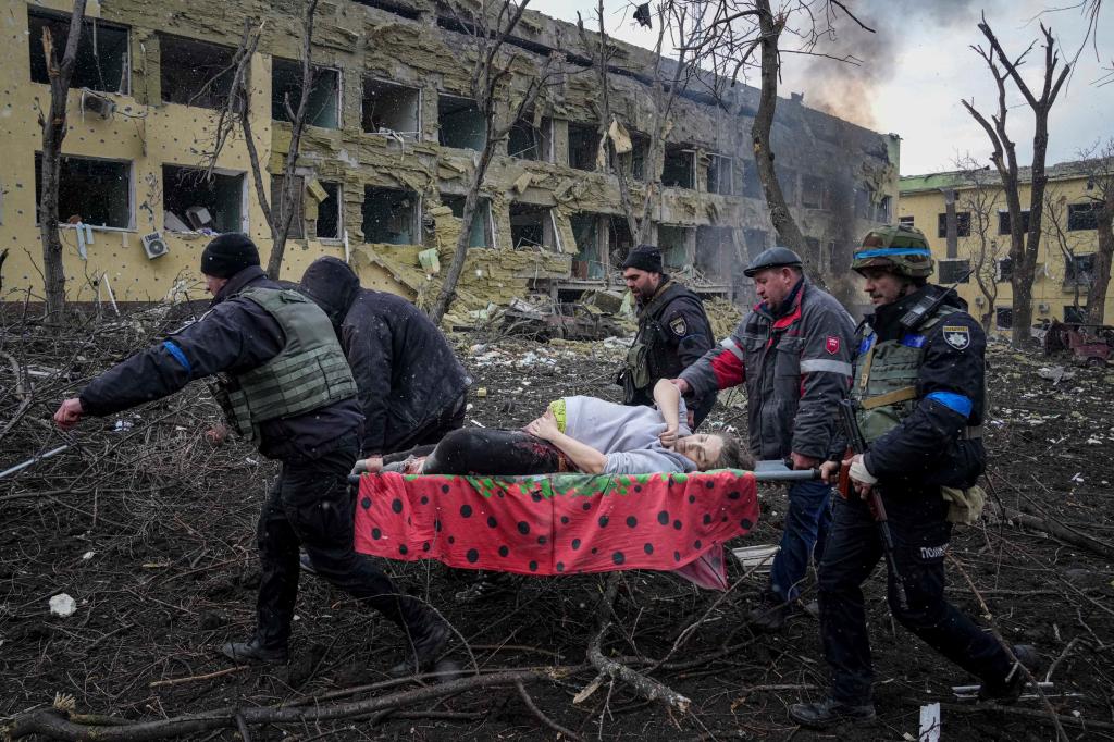 Ukrainian emergency employees and volunteers carry an injured pregnant woman from the damaged by shelling maternity hospital in Mariupol, Ukraine.