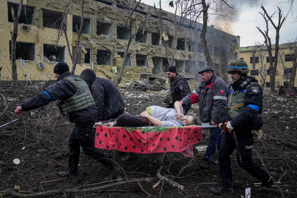 Ukrainian emergency employees and volunteers carry an injured pregnant woman from the damaged by shelling maternity hospital in Mariupol, Ukraine.