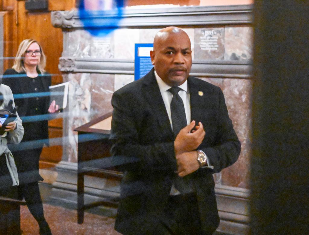 Carl Heastie walking in a hallway while he adjusts shirt cuff