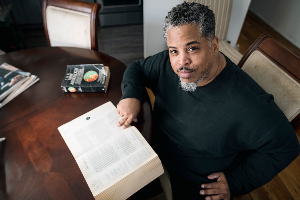 Lex DeCled at home in Brooklyn reading from an astrology book.