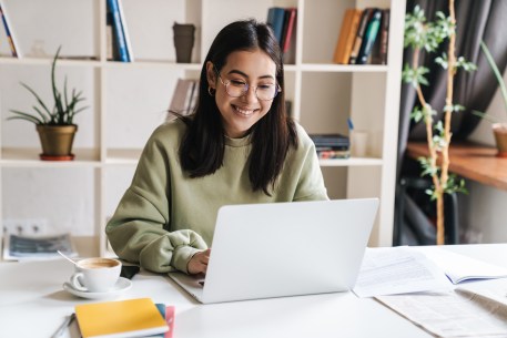 Student smiles while reviewing student loan refinance companies online