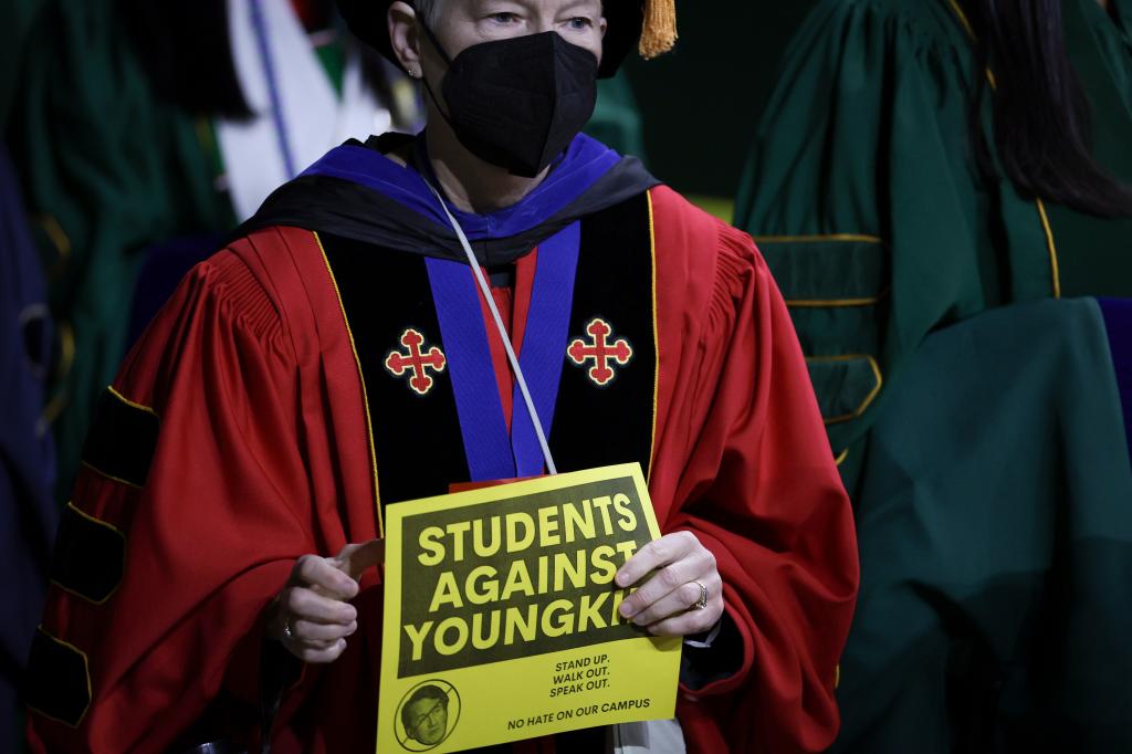 A faculty member carries a protest sign before Virginia Governor Glenn Youngkin (R-VA) spoke at George Mason University May 18, 2023 in Fairfax, Virginia. 