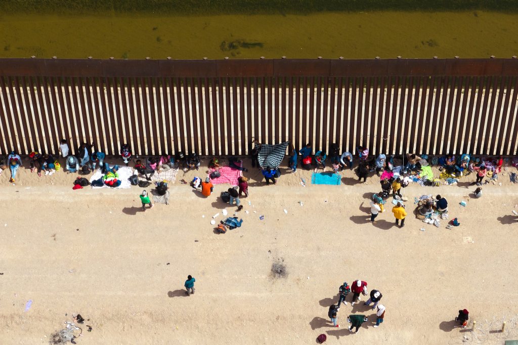 Migrants gathered by the border wall after crossing into the United States from Mexico on May 3, 2023.