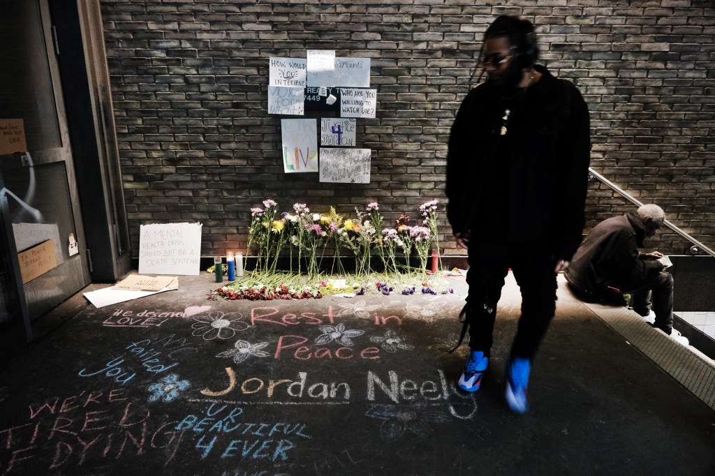 A person stands next to a tribute to Neely on the sidewalk. 