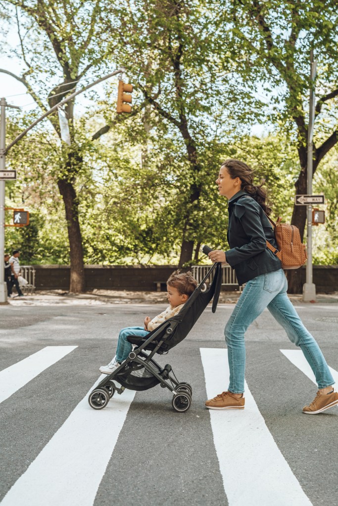 Woman crosses street with stroller. 