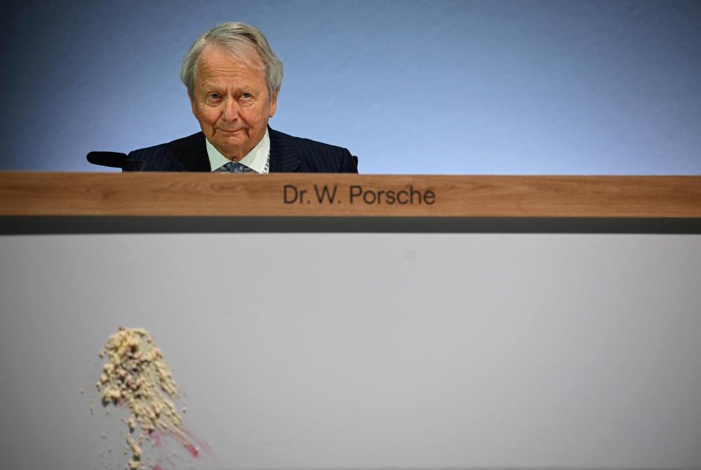 Director Wolfgang Porsche looks on fter a piece of cake has been thrown at the front of his desk.