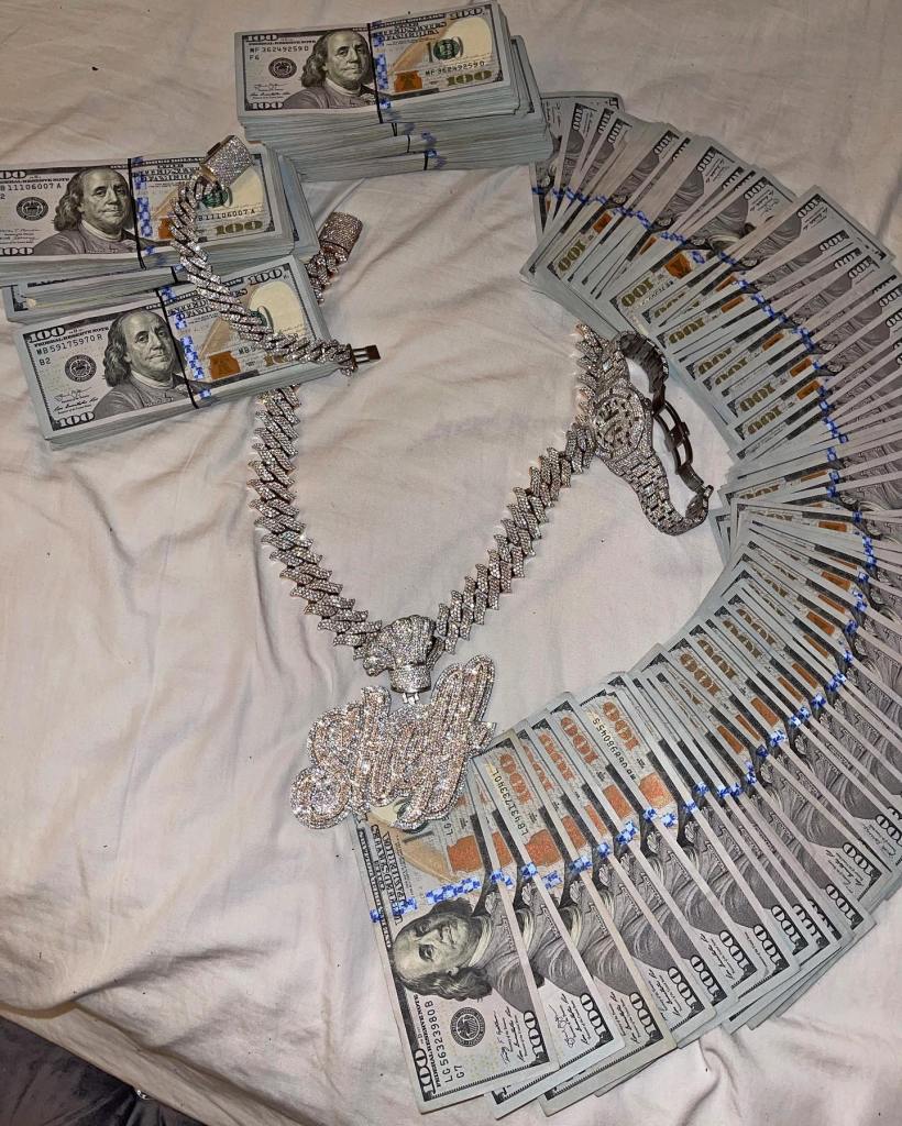 Hundred dollar bills fanned out on a bed.