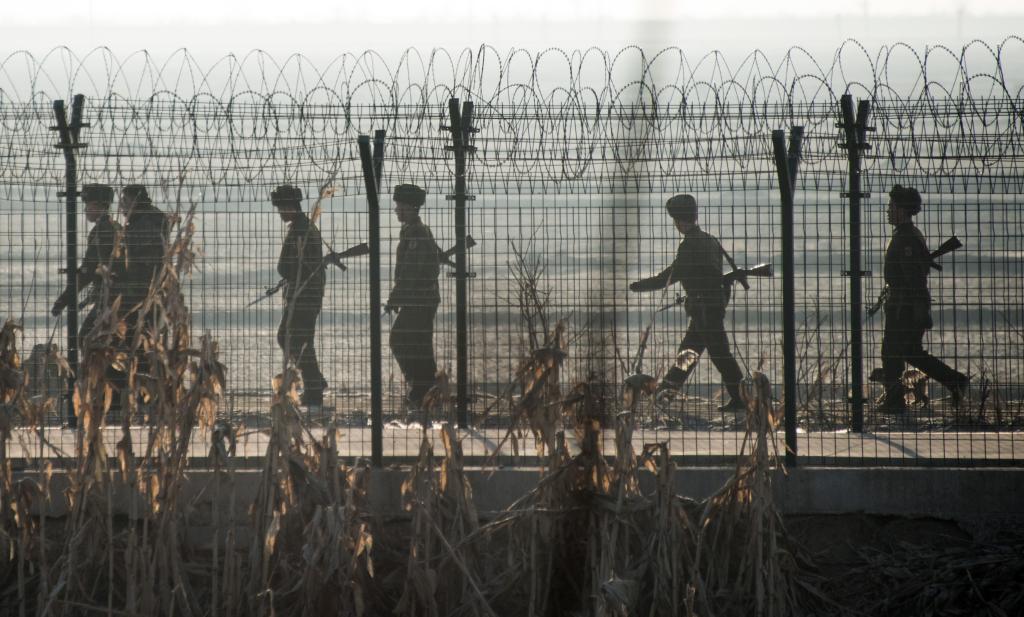 North Korean soldiers patrol next to the border fence near the town of Sinuiju across from the Chinese border town of Dandong on February 10, 2016.