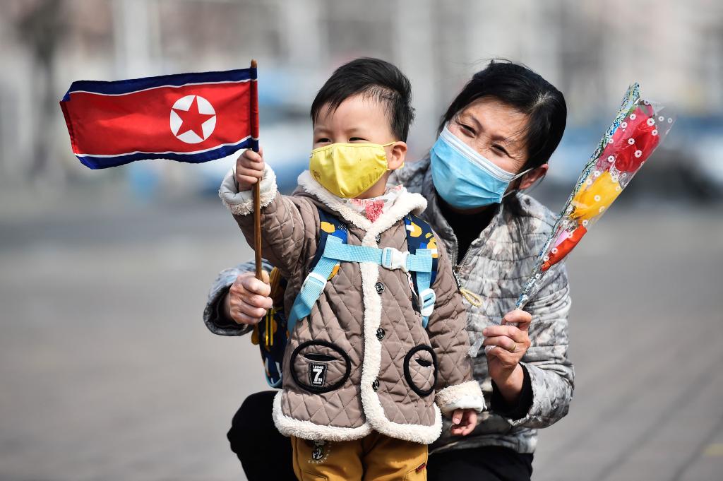 A Woman and her grandson wave North Korea's national flag in Pyongyang on March 8.