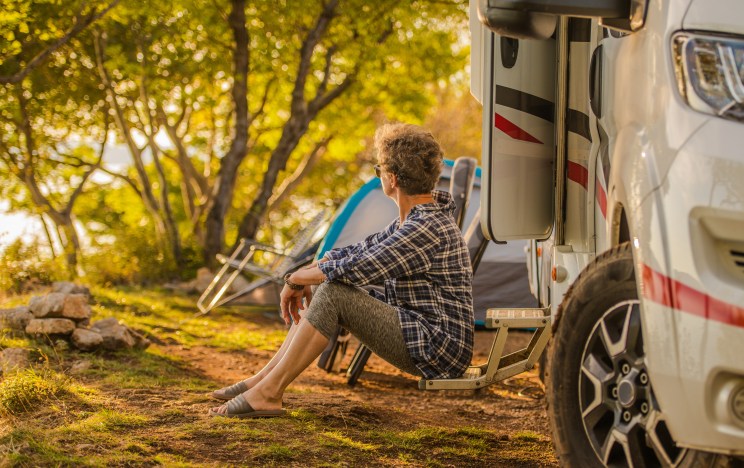 Woman sits outside her RV after financing it with a loan