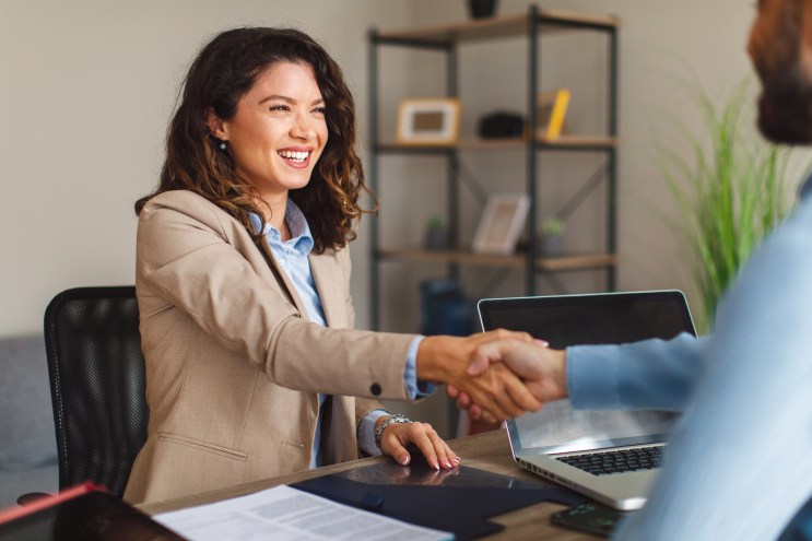 Bad-credit borrower shakes loan officer's hand after being approved for a debt consolidation loan