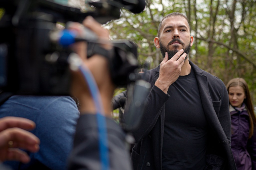 Andrew Tate touches his overgrown beard while arriving at court in Romania, where he remains under house arrest.