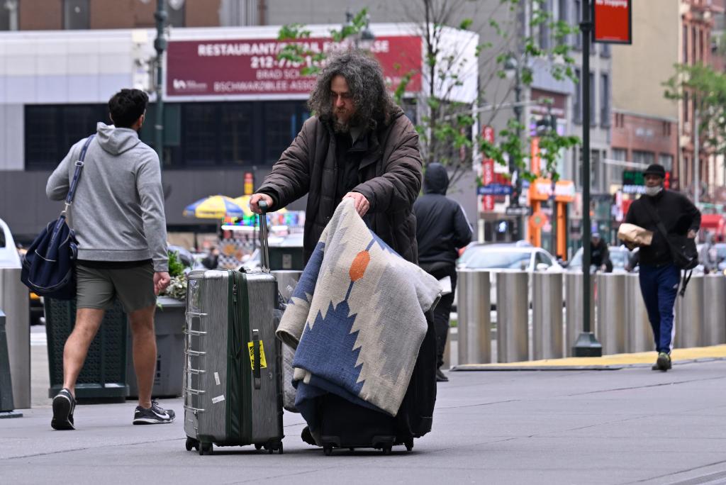 Homeless man pushes his belongings across from Penn Station.